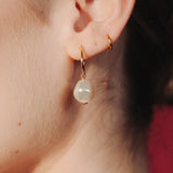 Close-up of an ear wearing a gold hoop earrings with a single vegan baroque pearl