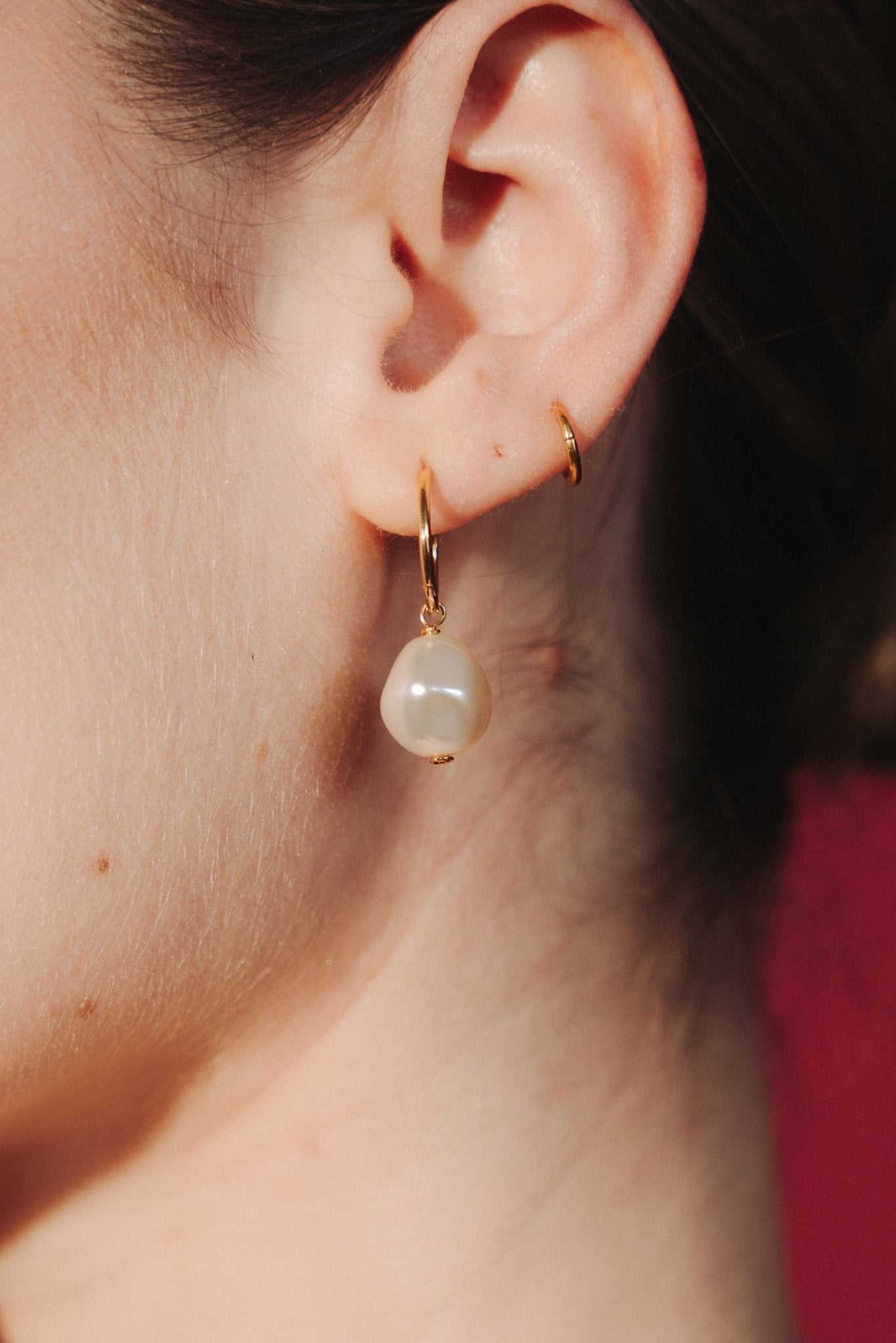 Close-up of an ear wearing a gold hoop earrings with a single vegan baroque pearl