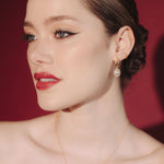 Bride wearing gold hoop earrings with a single vegan baroque pearl with a sleek low bun hair style and a matching gold pearl necklace