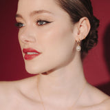 Bride wearing gold hoop earrings with a single vegan baroque pearl with a sleek low bun hair style and a matching gold pearl necklace