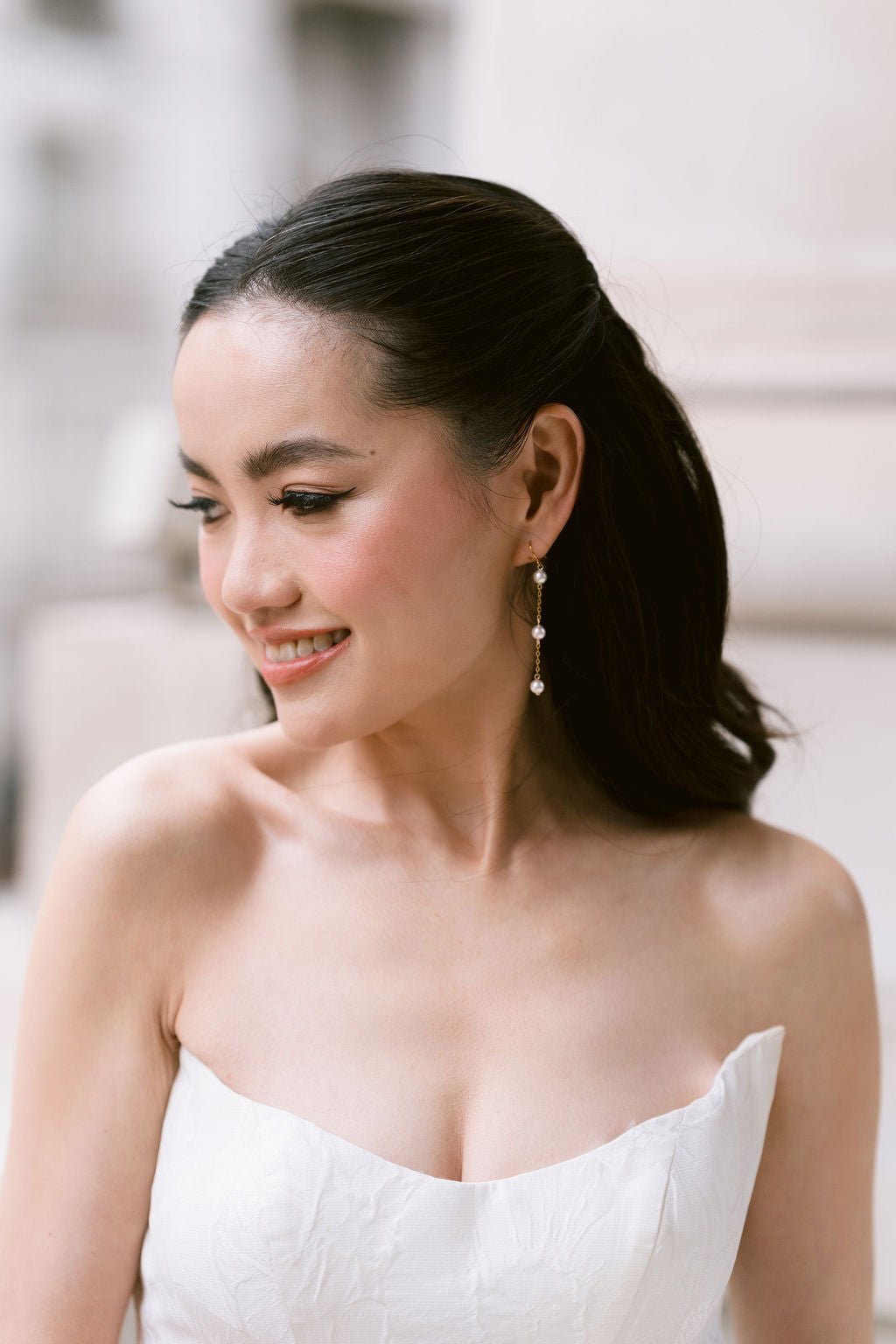 bride wears dainty pearl long drop earrings