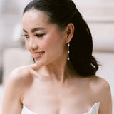 bride wears dainty pearl long drop earrings