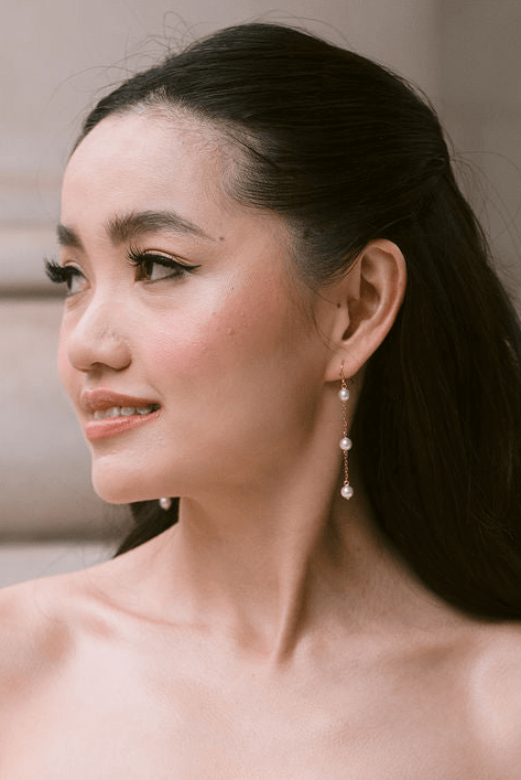 bride wears dainty pearl long drop earrings