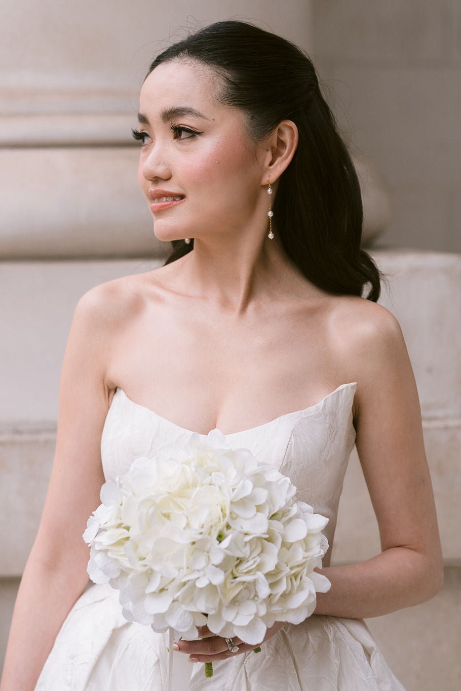 bride wears dainty pearl long drop earrings