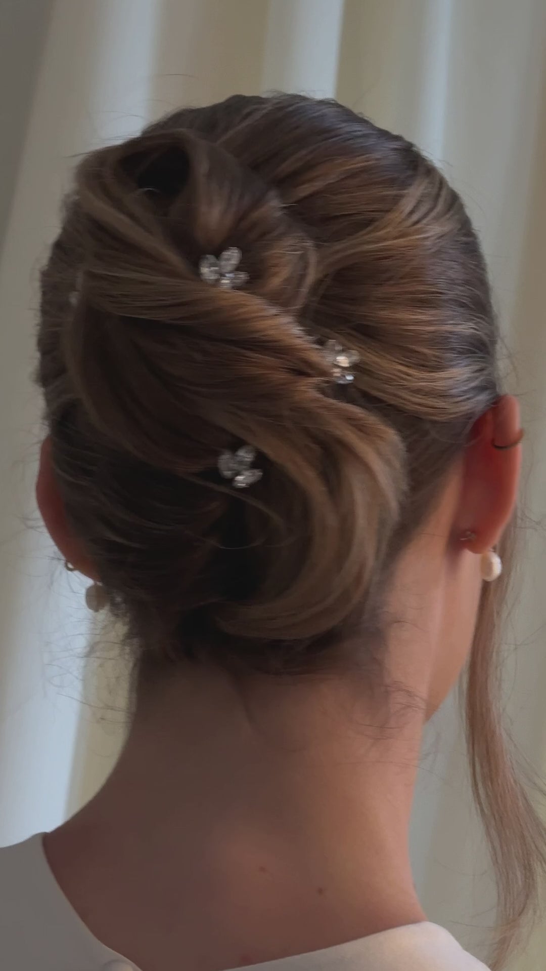 Bride wears small crystal hair pins in a French twist up do chignon