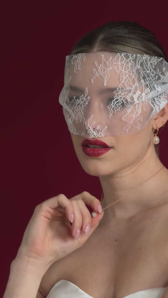 bride wears a lace mask style micro veilw with gold hoop baroque pearl earrings and matching necklace
