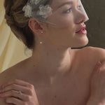bride wears dainty pearl drop earrings with a tulle mask veil and frace-framing silk flowers