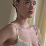 bride wears a mask style merry widow veil with pearl cluster hair pins at each side 