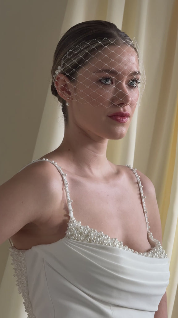bride wears a mask style merry widow veil with pearl cluster hair pins at each side 