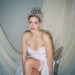 a bride wears a set of two stacked silver crystal crowns with matching hair pins extending over the top of her head s if growing from the tiara style base.