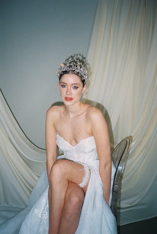 a bride wears a set of two stacked silver crystal crowns with matching hair pins extending over the top of her head s if growing from the tiara style base.