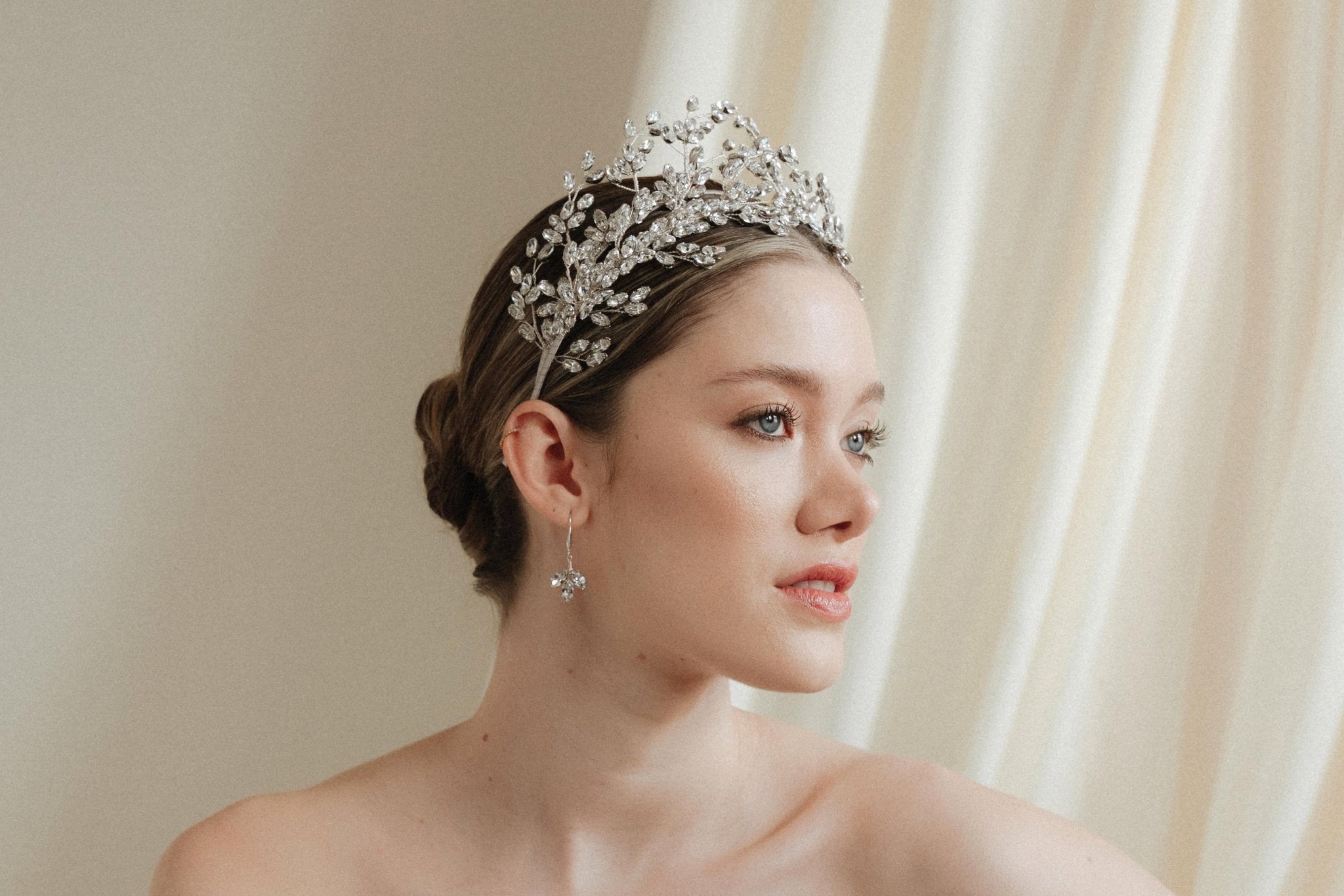 a bride wears a set of two stacked silver crystal crowns with matching hair pins extending over the top of her head s if growing from the tiara style base.