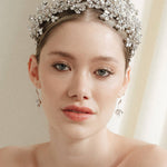 a bride wears a set of two stacked silver crystal crowns with matching hair pins extending over the top of her head s if growing from the tiara style base.