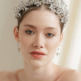 a bride wears a set of two stacked silver crystal crowns with matching hair pins extending over the top of her head s if growing from the tiara style base.