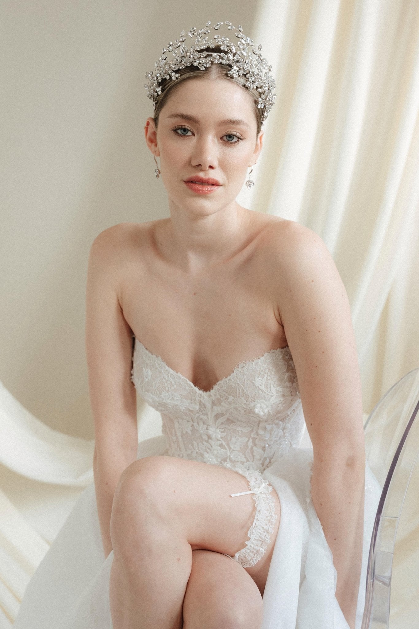 a bride wears a set of two stacked silver crystal crowns with matching hair pins extending over the top of her head s if growing from the tiara style base.