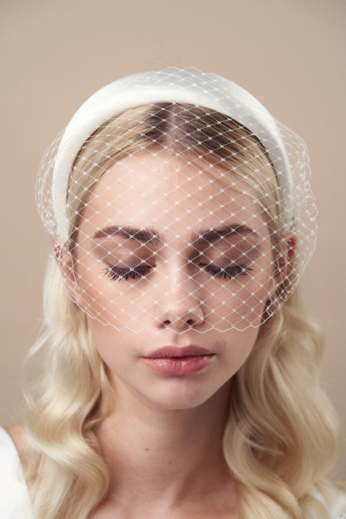 Ivory padded headband with adjustable birdcage veil worn above the mouth