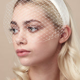 Ivory padded headband with adjustable birdcage veil attached worn above the mouth