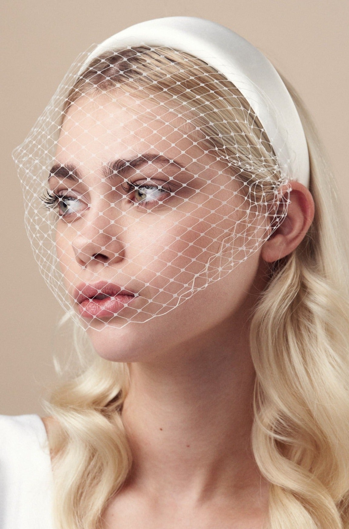 Ivory padded headband with adjustable birdcage veil attached worn covering the mouth