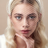 Ivory padded headband with adjustable birdcage veil worn above the mouth