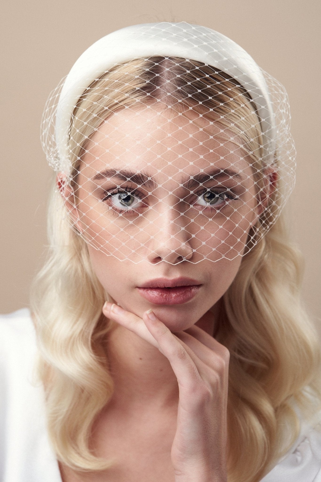 Ivory padded headband with adjustable birdcage veil worn above the mouth