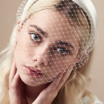 Ivory padded headband with adjustable birdcage veil attached worn covering the mouth